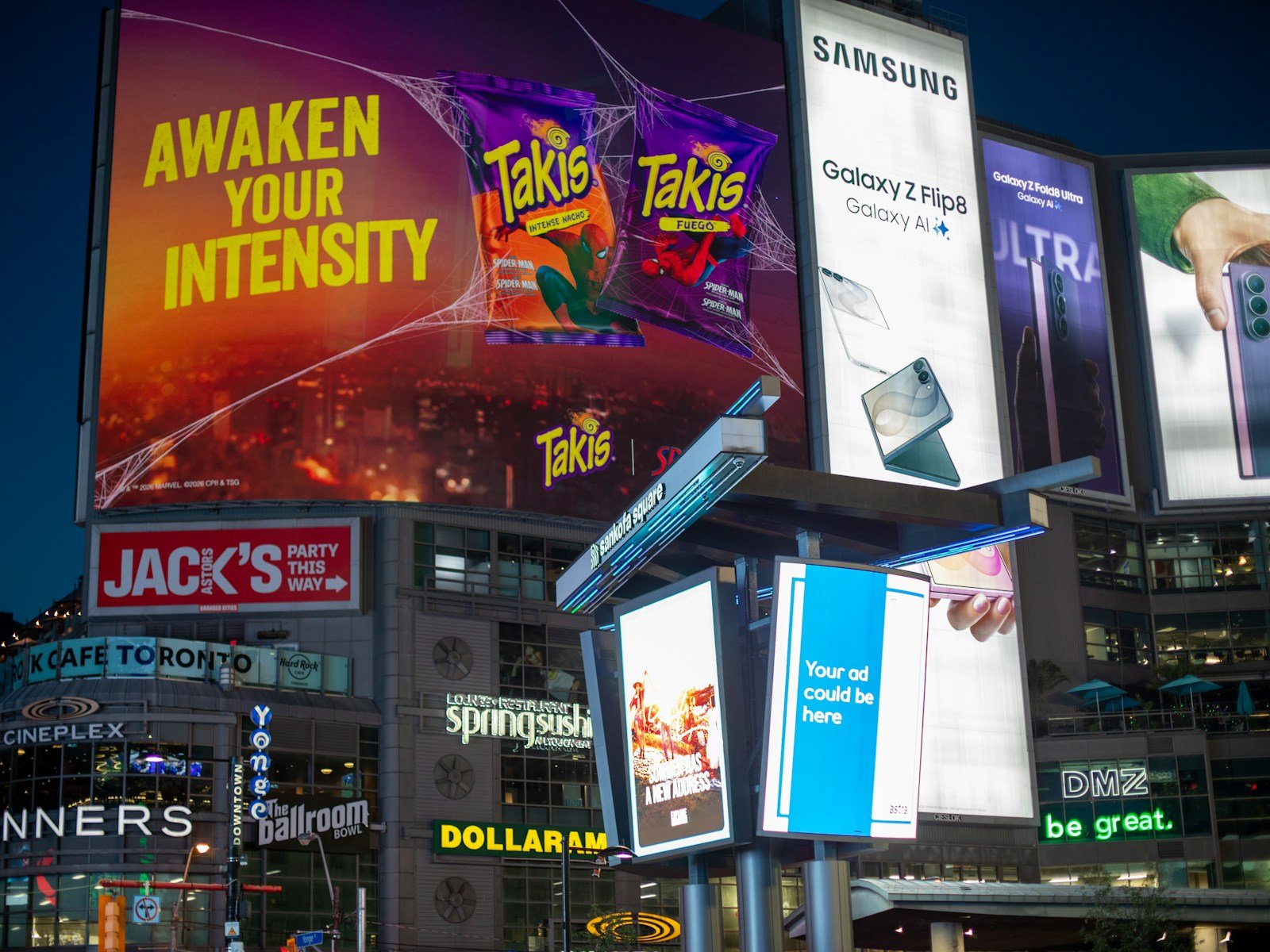Bright digital billboards illuminate a city square at night